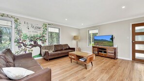 Ein Wohnzimmer mit einem braunen Ledersofa, einem Holztisch und einem Fernseher auf einem Holzgestell.
