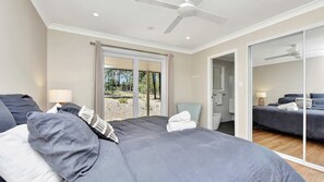 A bedroom with a large bed, a ceiling fan, a sliding glass door leading to a balcony, and a mirrored closet. - La Villetta | Stunning Views (Pokolbin)