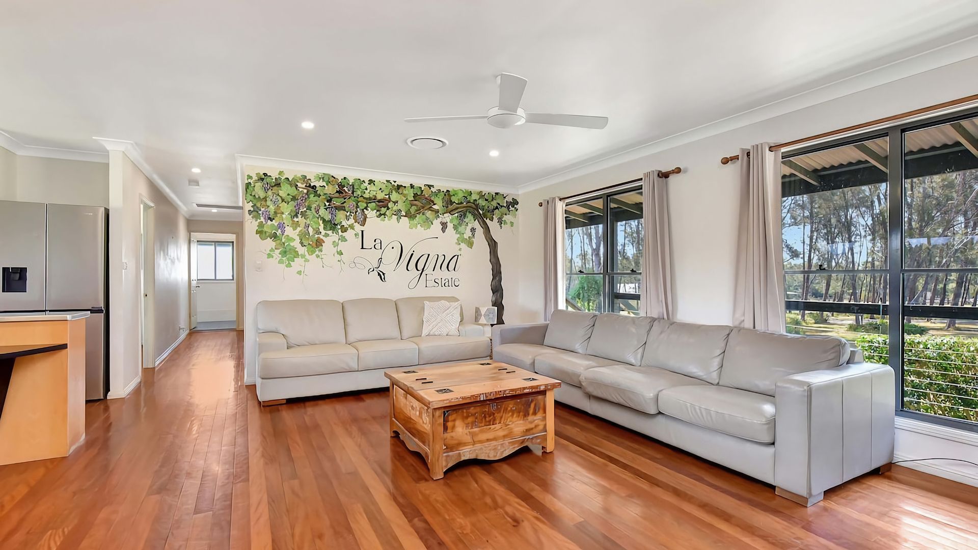 A modern living room with a sectional sofa, a wooden coffee table, and a wall mural.