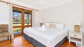 A hotel room with a large bed, two bedside lamps, a nightstand, and a chair.