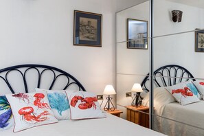 Quarto de hotel com cama, duas mesas de cabeceira, um espelho e almofadas decorativas.