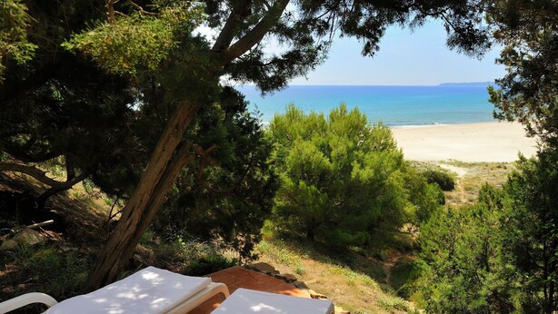 Vista sulla spiaggia con due lettini e un sentiero in pietra.