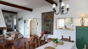 Un'area pranzo con tavolo, sedie, un lampadario, un quadro e un mobiletto verde.
