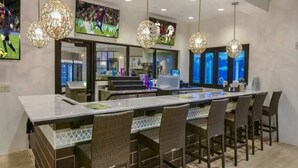 Une cuisine moderne dotée d’un grand îlot central, de luminaires suspendus et de décorations murales sur le thème du sport.