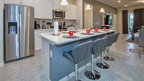 Une cuisine moderne dotée d’un îlot central, d’appareils électroménagers en acier inoxydable et de tabourets de bar.