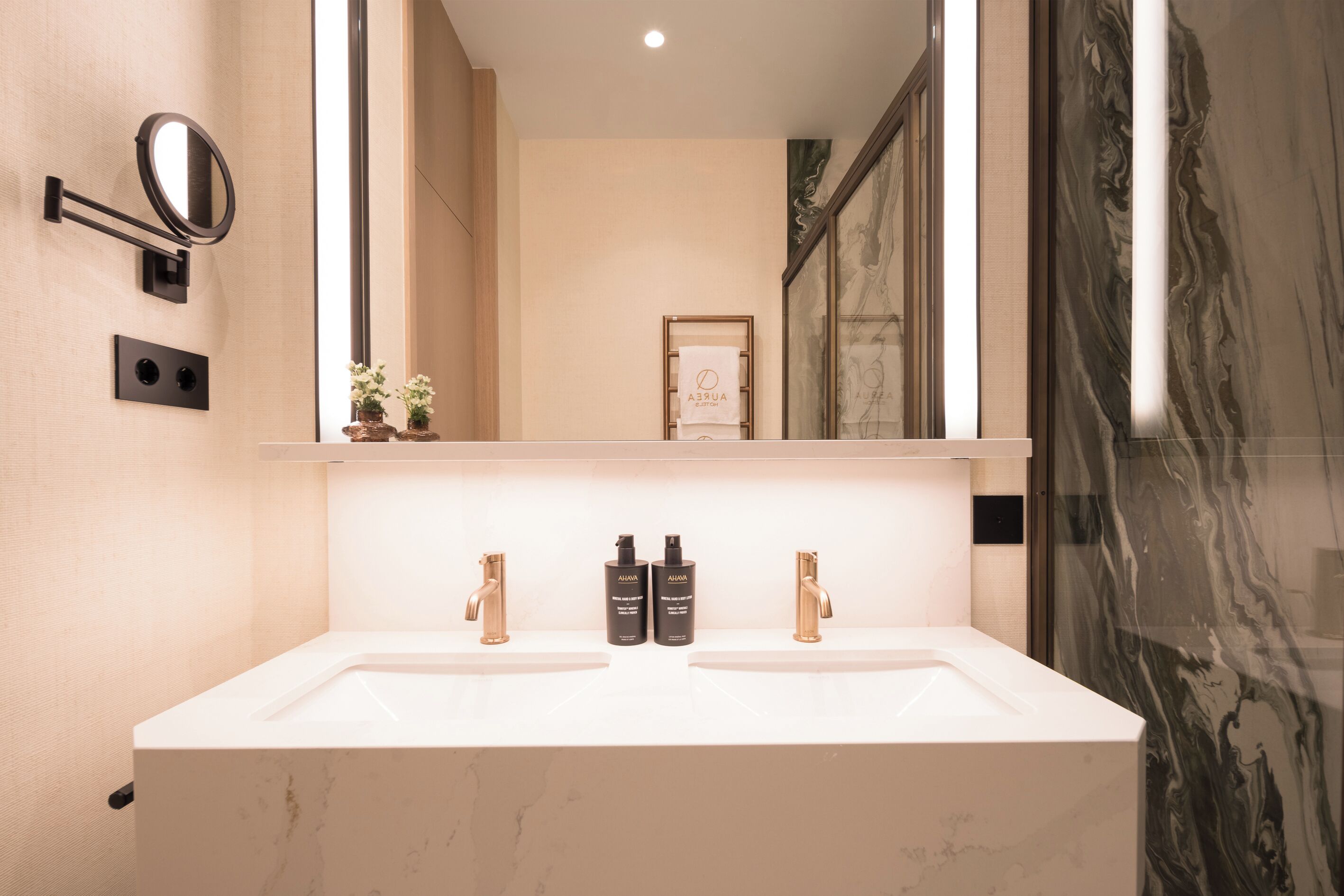 A bathroom with a large mirror, two sinks, and a towel rack.