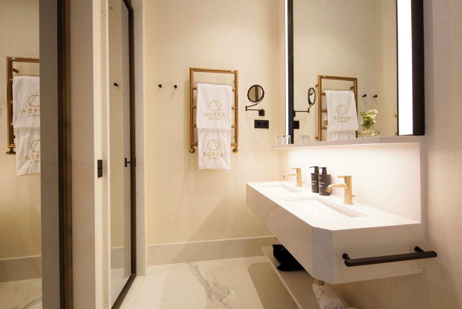 Un baño moderno con tocador blanco, detalles dorados y un espejo grande.