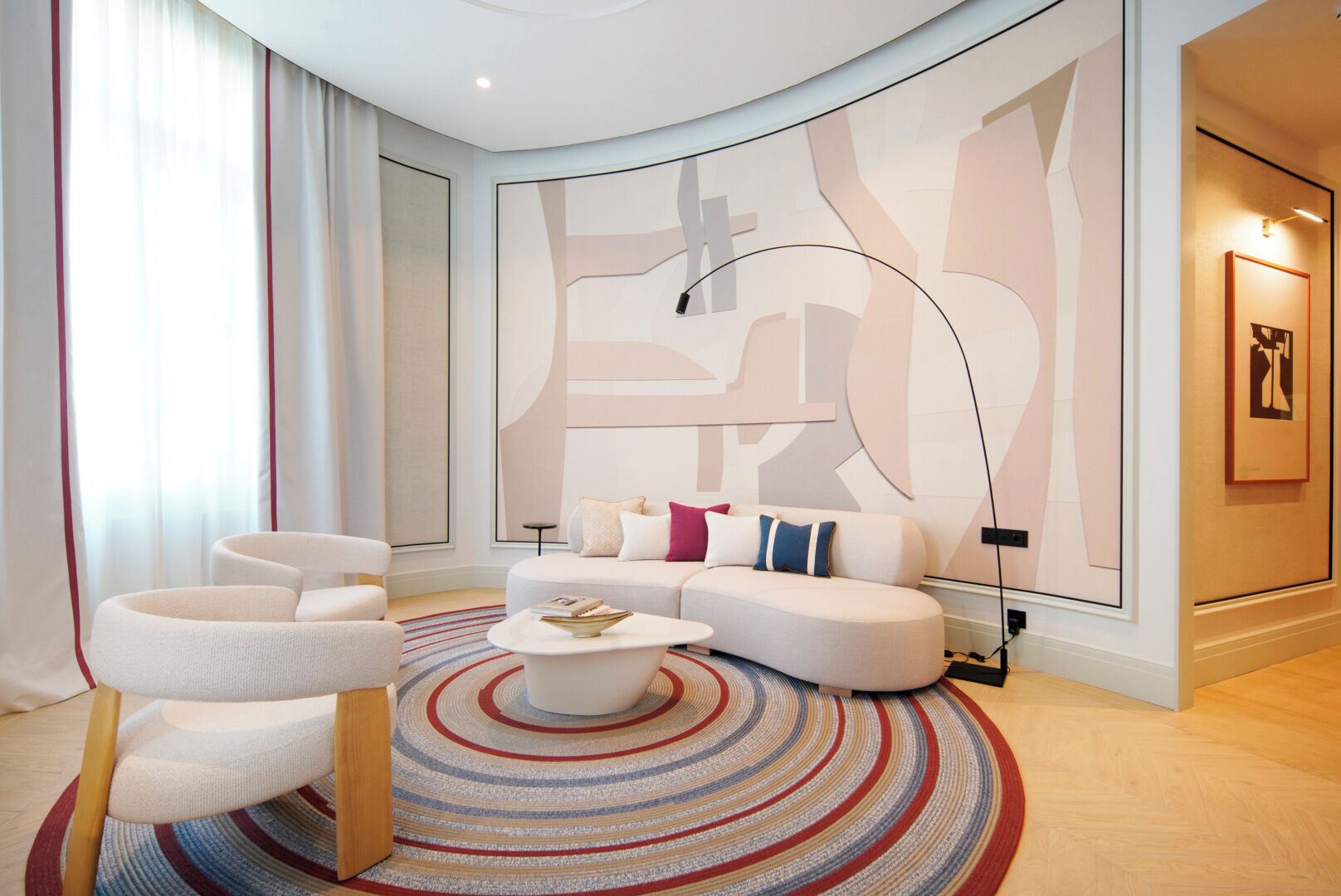 A modern living room with a sectional sofa, a round coffee table, and a large abstract wall art piece.