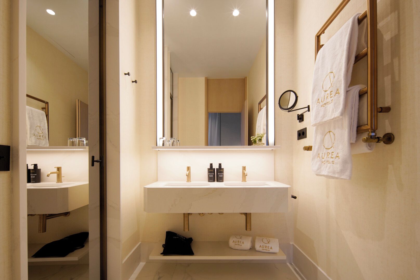 Un baño moderno con un espejo grande, un lavamanos blanco y dos barras para toallas con toallas de marca.