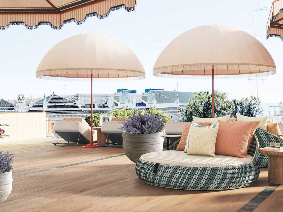 A rooftop terrace with round seating, umbrellas, and potted plants.