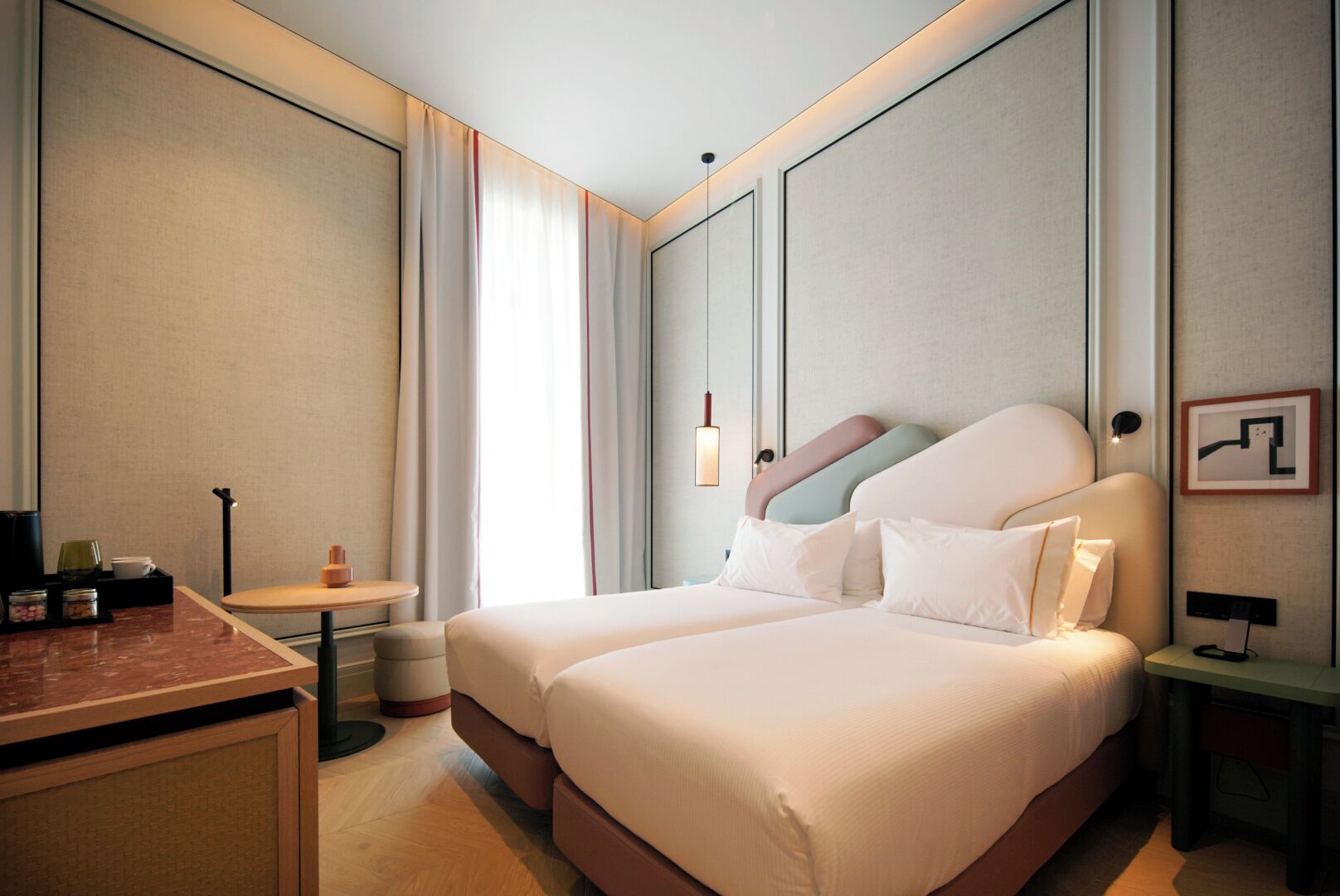 Ein Hotelzimmer mit zwei Betten, einem kleinen Tisch, einem Stuhl, einem Schreibtisch und einem Nachttisch.