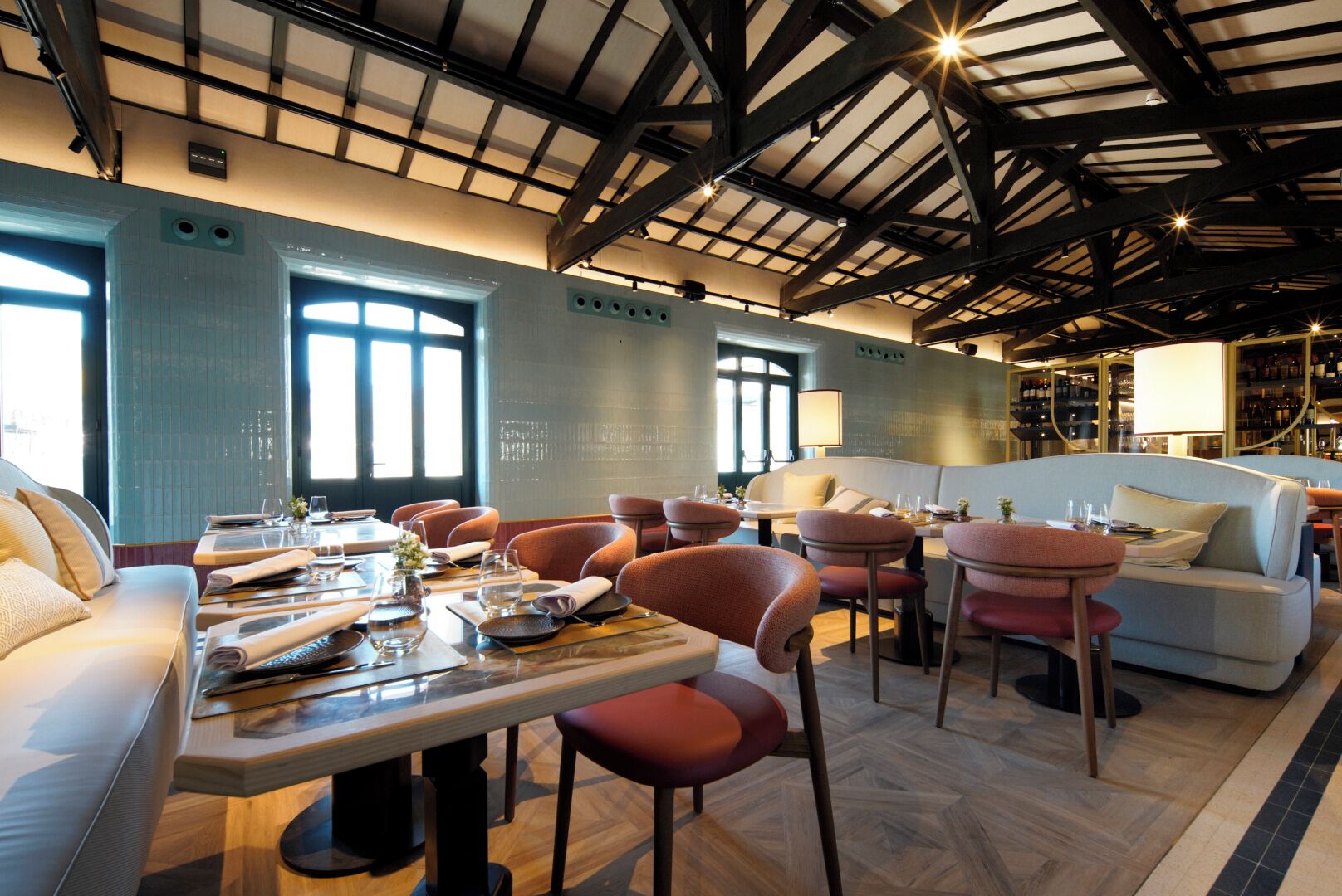 Un comedor con mesas y sillas, un sofá y una zona de bar con botellas.