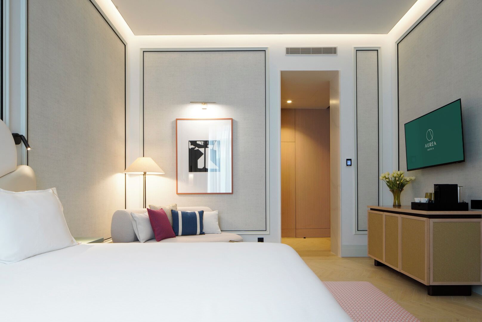 A hotel room with a bed, a desk, a TV, and a framed picture on the wall.