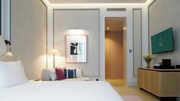 A hotel room with a bed, a desk, a TV, and a framed picture on the wall.