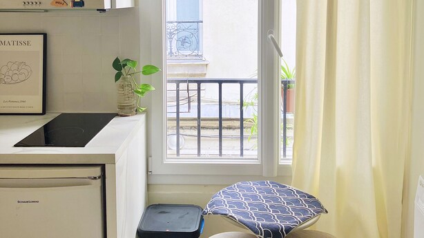 Una cucina compatta con un forno a microonde, un piccolo cestino e una finestra che si affaccia sul balcone esterno.