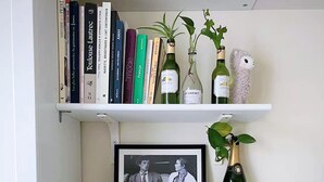 Una mensola ordinata con libri, una fotografia incorniciata e oggetti decorativi, tra cui una macchina da caffè e un cesto.