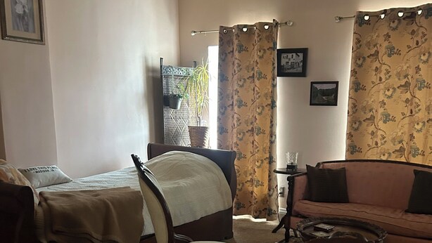 Een gezellige kamer met een bed, een stoel, een bank en een kleine tafel.