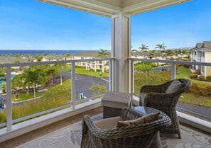 A balcony with wicker furniture and a view of the ocean and neighboring houses. - Summer Deal Kona Ocean View Villa with Pool Hot Tub and Beach Gear (Kailua-Kona)
