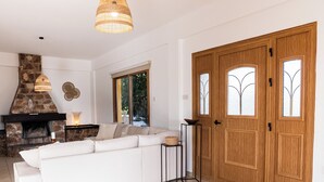 Un soggiorno moderno con camino in pietra, divano bianco e ampia porta in legno con pannelli di vetro.