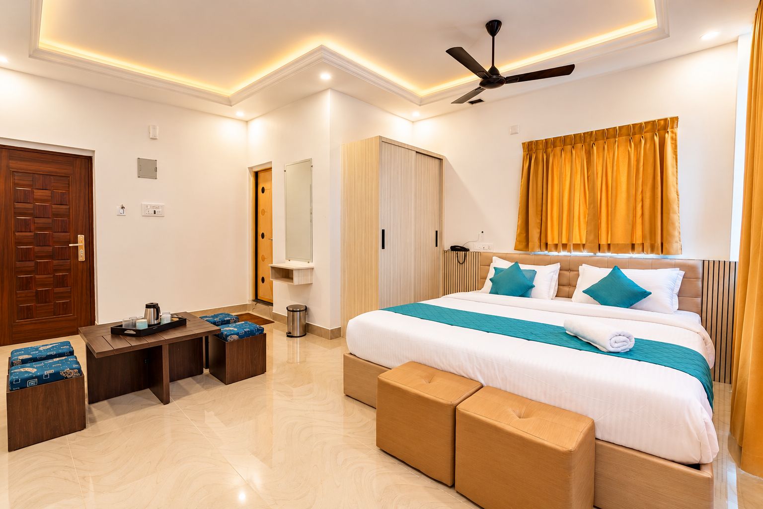 A hotel room with a bed, bedside table, and a seating area with cushions.