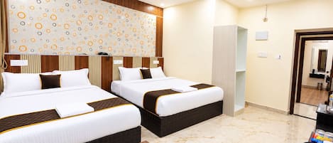 A hotel room with two beds, a wooden floor, a patterned wall, and a ceiling fan.