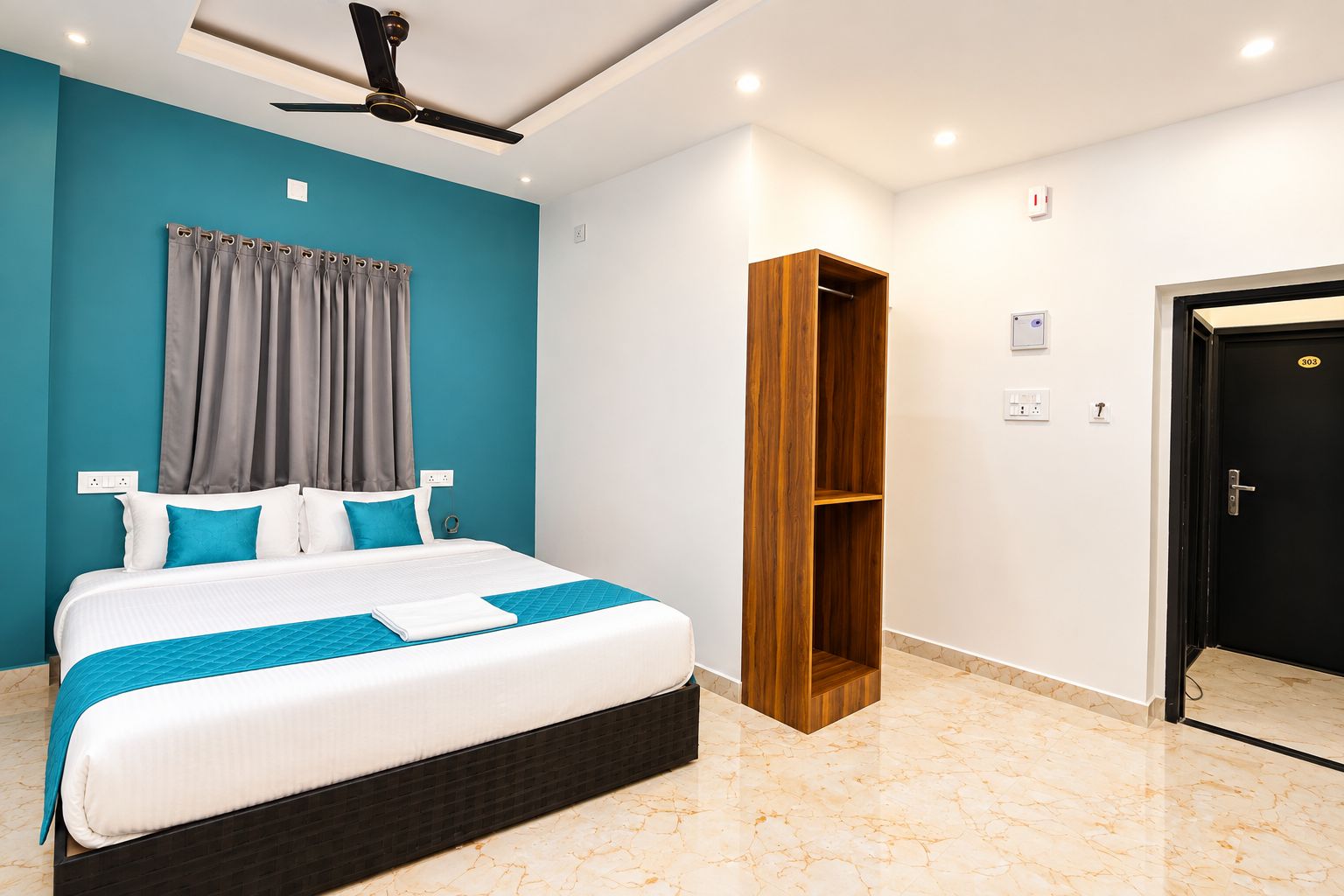 Une chambre d’hôtel avec un lit, un ventilateur de plafond, une armoire et une porte.