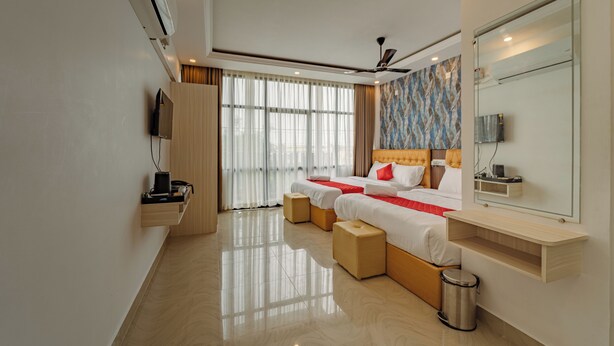A modern hotel room with a large bed, a desk, and a TV. - Priya Residency Pondicherry (Vanur)