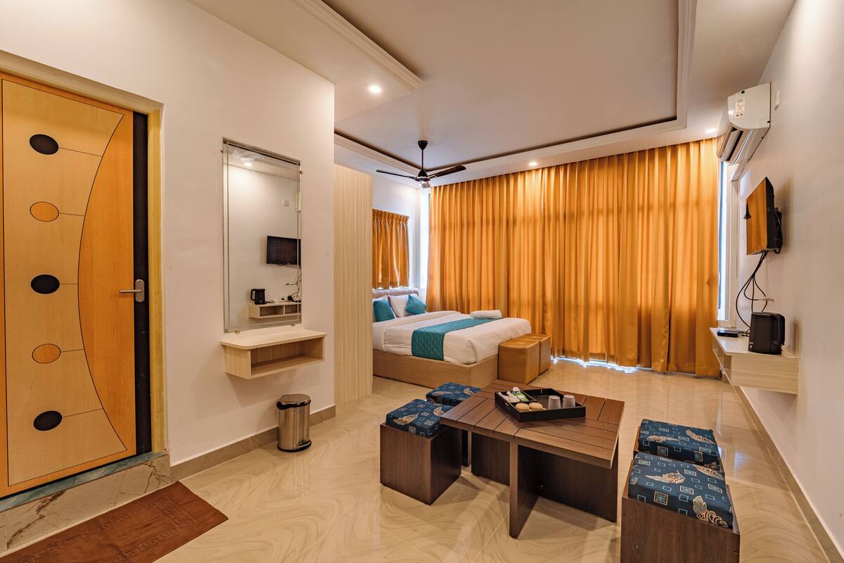 Una habitación de hotel moderna con una cama, un escritorio, una silla, un televisor y una ventana con cortinas.