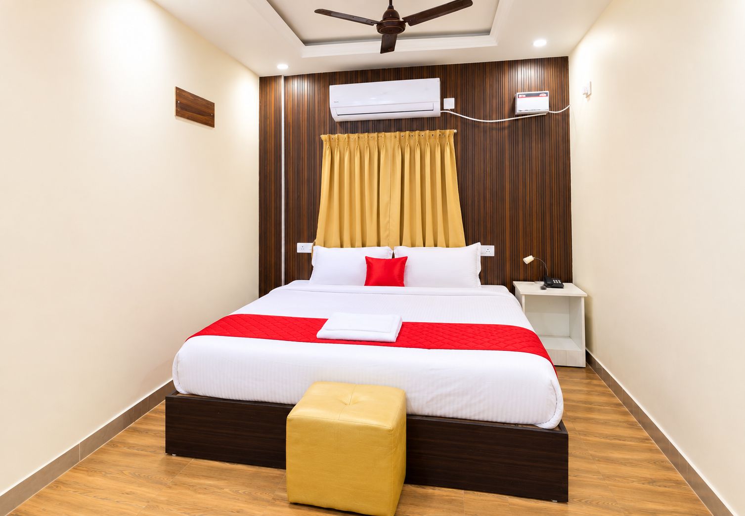 A hotel room with a bed, bedside table, and a ceiling fan.