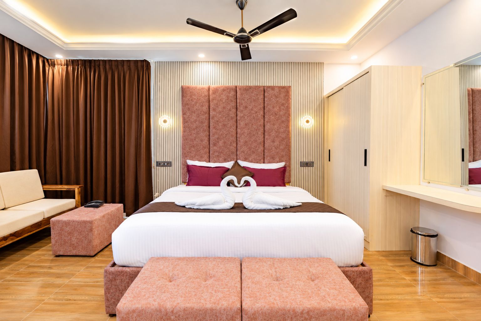 Une chambre d’hôtel avec un grand lit, un ventilateur de plafond, un canapé et une petite table.