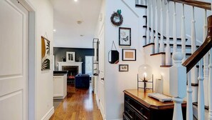 A hallway with a staircase, wooden flooring, and a fireplace. - Hôtel à la maison - Entre Mont et rivière (Orford)