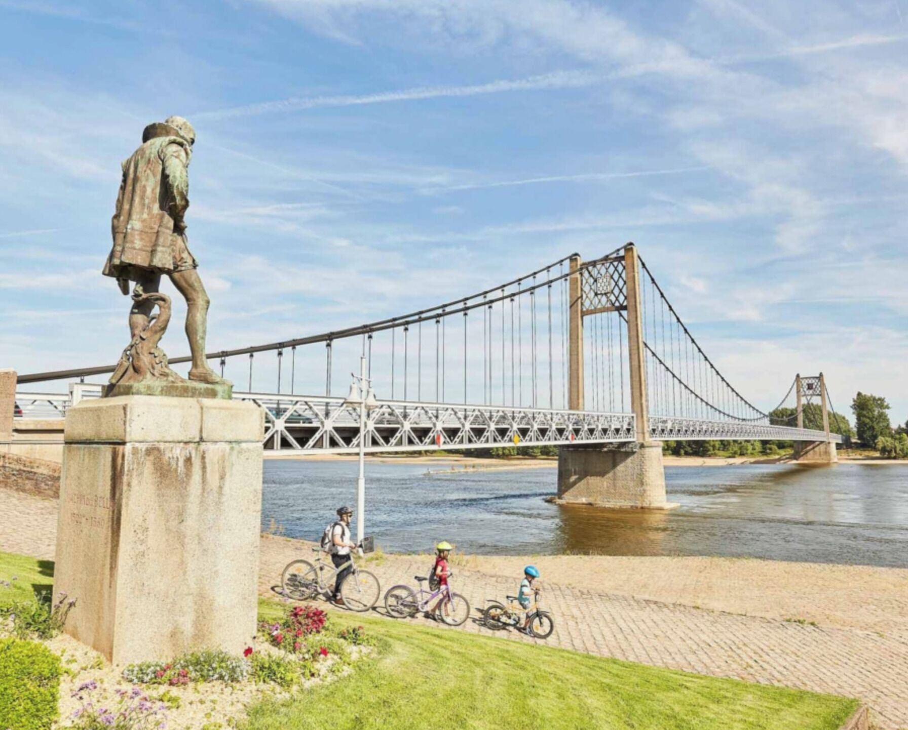 A suspension bridge with a statue in the foreground.