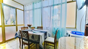 A dining area with a table set for four, chairs, a vase with flowers, and sheer curtains on the windows. - Large Apartment in Tropea Center for max 10 people, free parking, near station (Tropea)