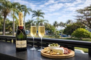 A bottle of Moët & Chandon champagne, two glasses of champagne, and a cheese and charcuterie board on a balcony with a view of palm trees. - Strand Stay just Steps to Beach & Waterpark - 2BR Beach Front Townsville (North Ward)