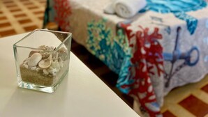A hotel room with a bed, a nightstand, and a glass container with seashells. - Cozy Apartment in Center of Tropea, 5 min from Station, free parking (Tropea)