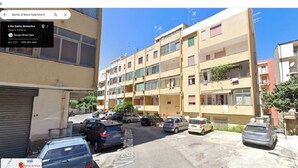 A multi-story residential building with several balconies, a parking lot with various cars, and a clear blue sky. - Cozy Apartment in Center of Tropea, 5 min from Station, free parking (Tropea)