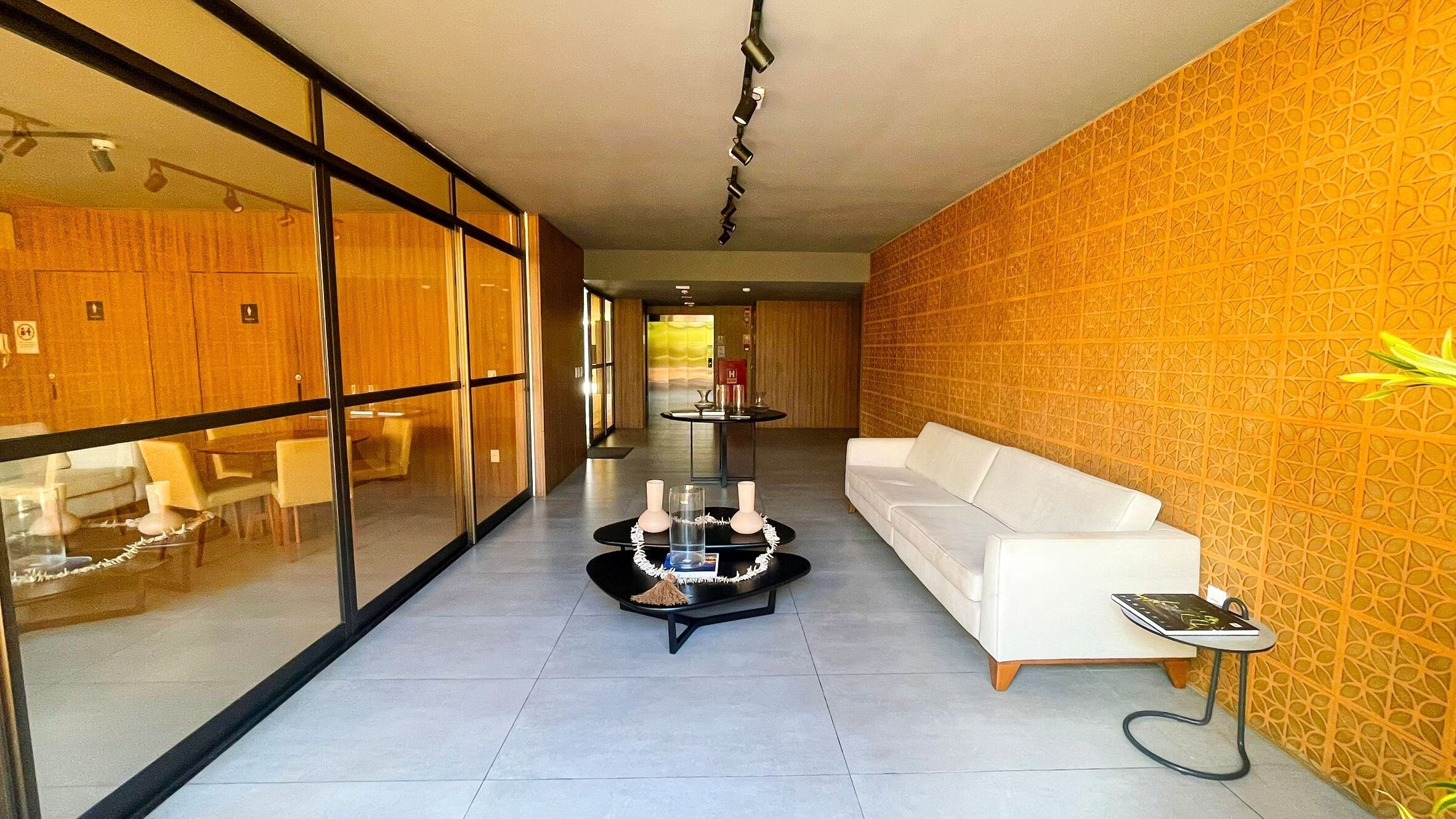 A modern hotel lobby with a white sofa, a glass partition, and a patterned wall.