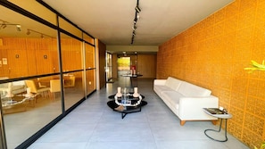 A modern hotel lobby with a white sofa, a glass partition, and a patterned wall. - FM20 Cabo Branco Light III - By Almare (João Pessoa)