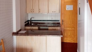 A compact kitchen with wooden cabinets, a sink, and a stove.