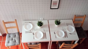 A dining table set for four with chairs, a small potted plant, and a framed picture on the wall.