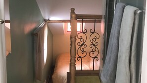 A compact bedroom with a single bed, a wooden headboard, a small window, and a shower area. - Very charming 1 bed room in heart of paris with balcony (Paris)