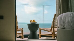 A room with a view of the sea, a round table with a bowl of fruit, and two wicker chairs. - Orizontas Suites 2 Syvota (Igoumenitsa)