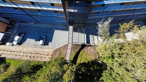 Vista aérea de un edificio con techo azul, paneles solares y un estacionamiento con dos autos.