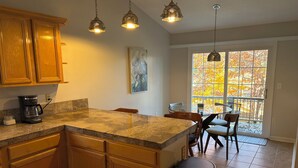 A kitchen with wooden cabinets, a granite countertop, a coffee maker, and pendant lights. - Peaceful Two Bedroom Apartment in Charming Weaverville. (Weaverville)