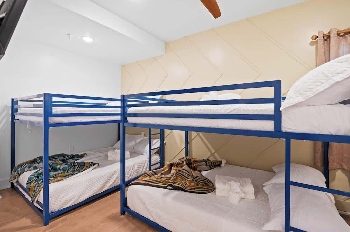 A room with bunk beds, a ceiling fan, and a light fixture.