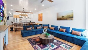 A modern living room with a blue sofa set, a round coffee table, and a wooden floor. - Summit Stay Near Kalahari & Raceway (Pocono Summit)