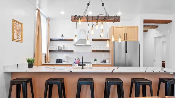 A modern kitchen with a central island, bar stools, and a hanging light fixture. - Summit Haus  Cozy Getaway in the Poconos (Pocono Summit)