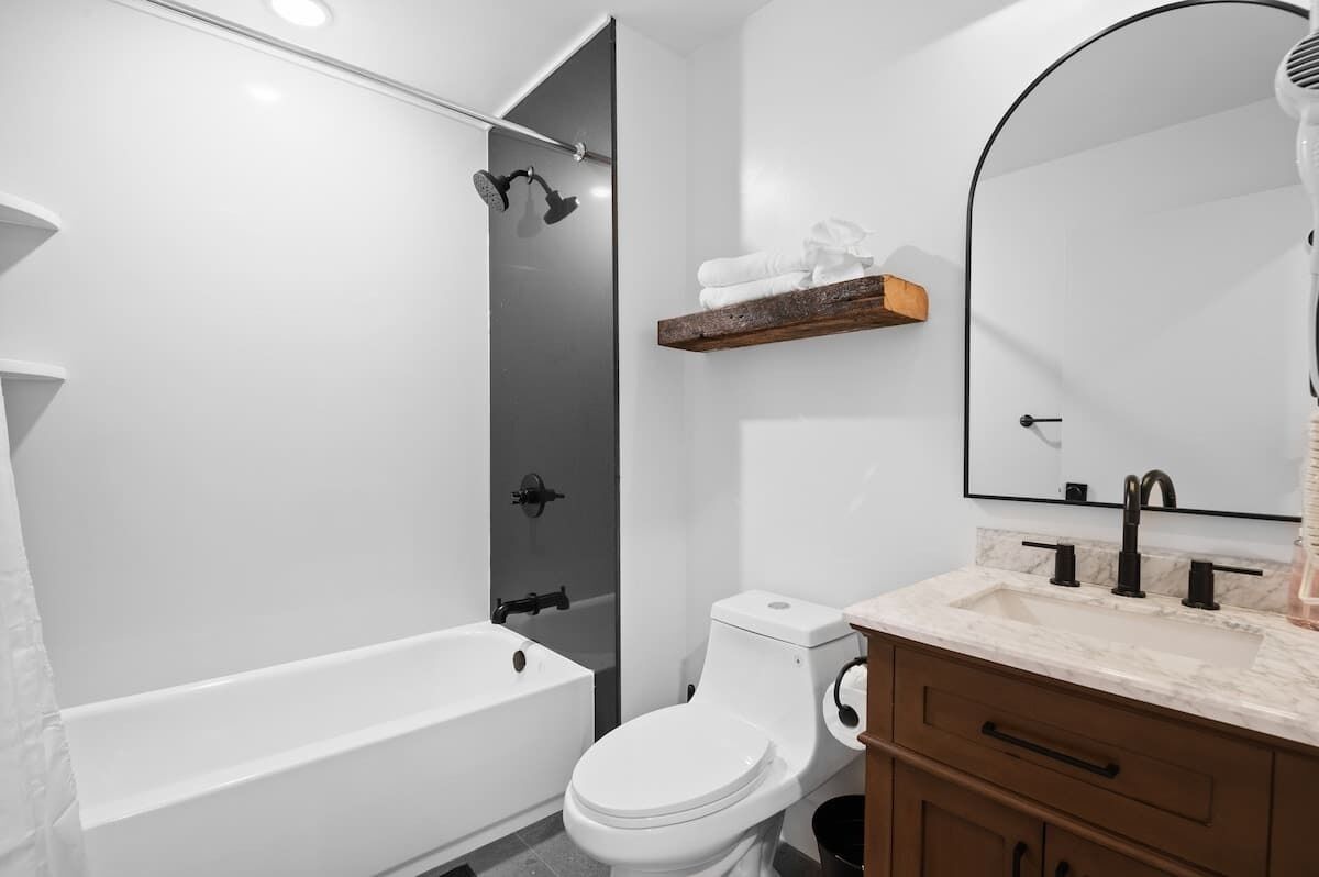 Un baño moderno con bañera, inodoro y tocador con espejo.