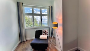 Een hoekappartement met raam, een zwarte bank, een lamp en een radiator.