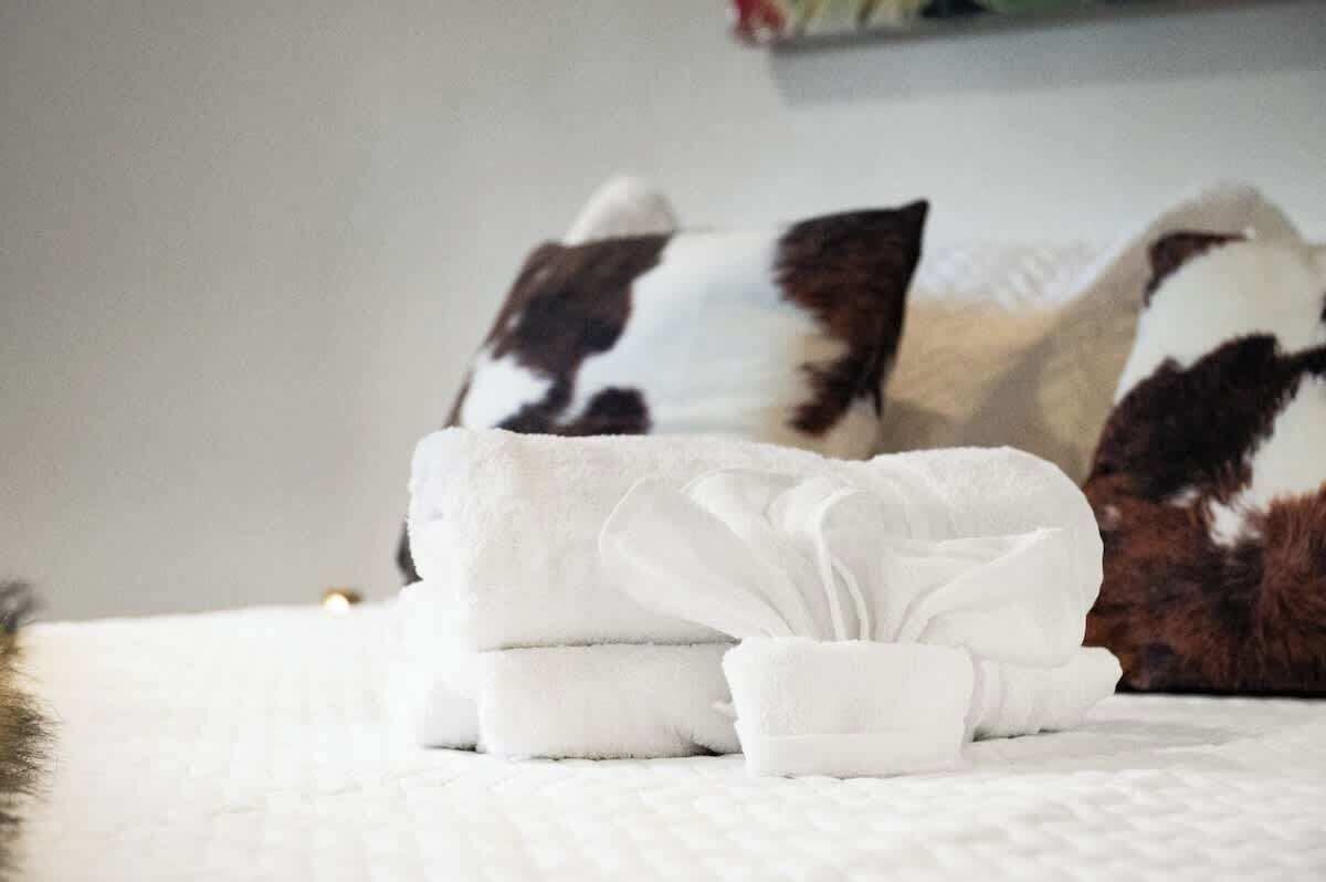 A neatly made bed with white bedding and a folded white towel.